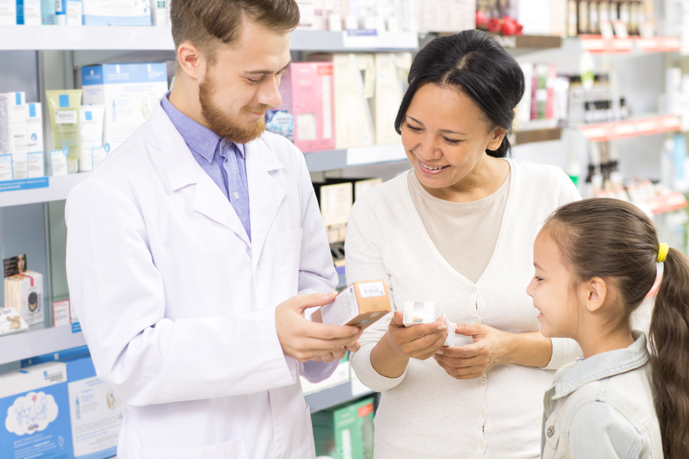 Male,pharmacist,helping,his,customers,mother,and,little,daughter,with
